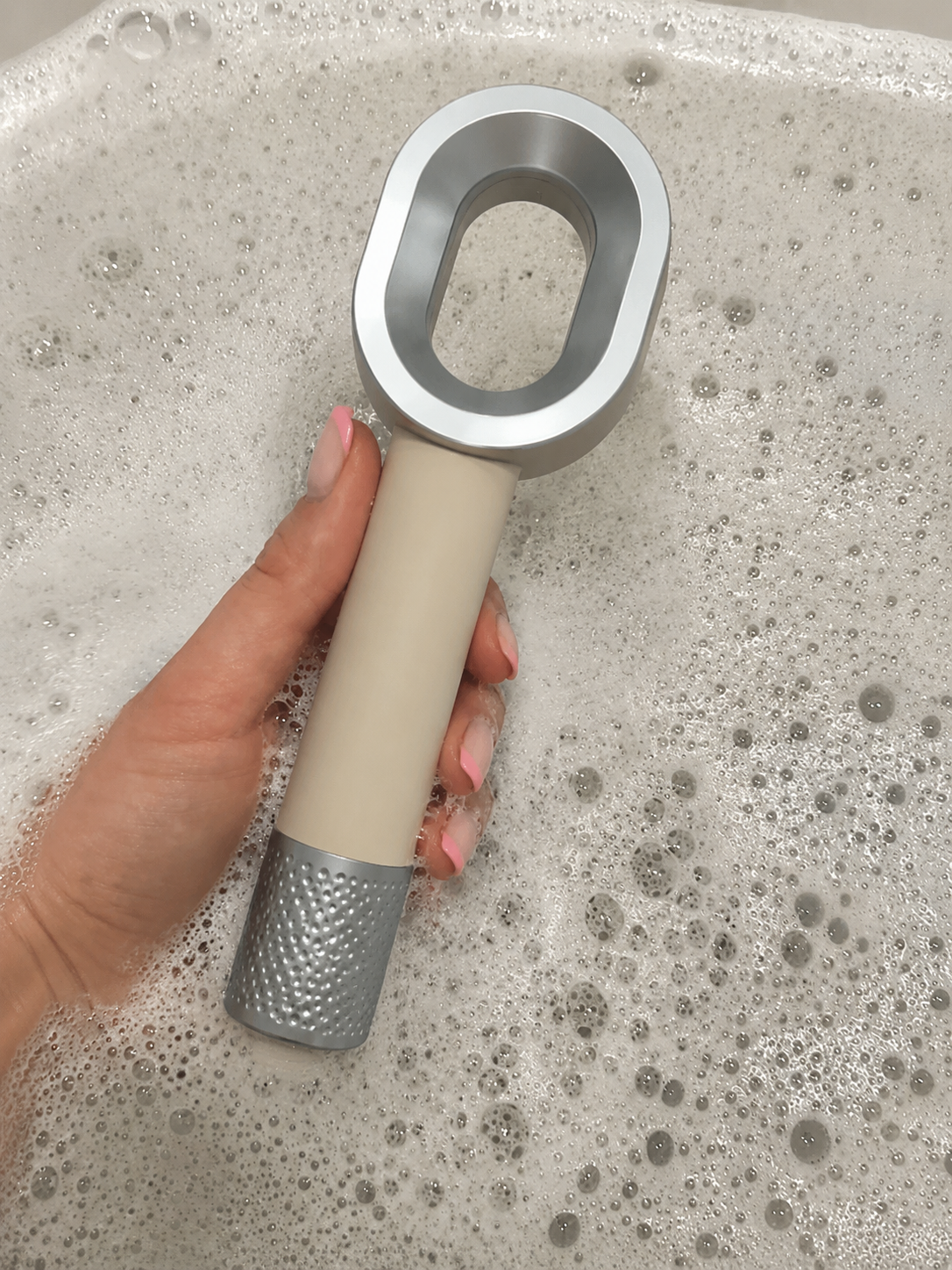 Image du pommeau filtrant beige Suimy avec filtre ACF anti chlore et anti calcaire, dans un bain. 
